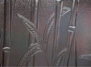 A close up of a glass door with bamboo leaves on it.