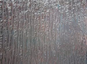 A close up of a window with water drops on it.